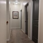 A hallways with white colored whiles and dark grey doors