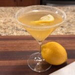 Lemon drop martini in martini glass with lemon on cutting board