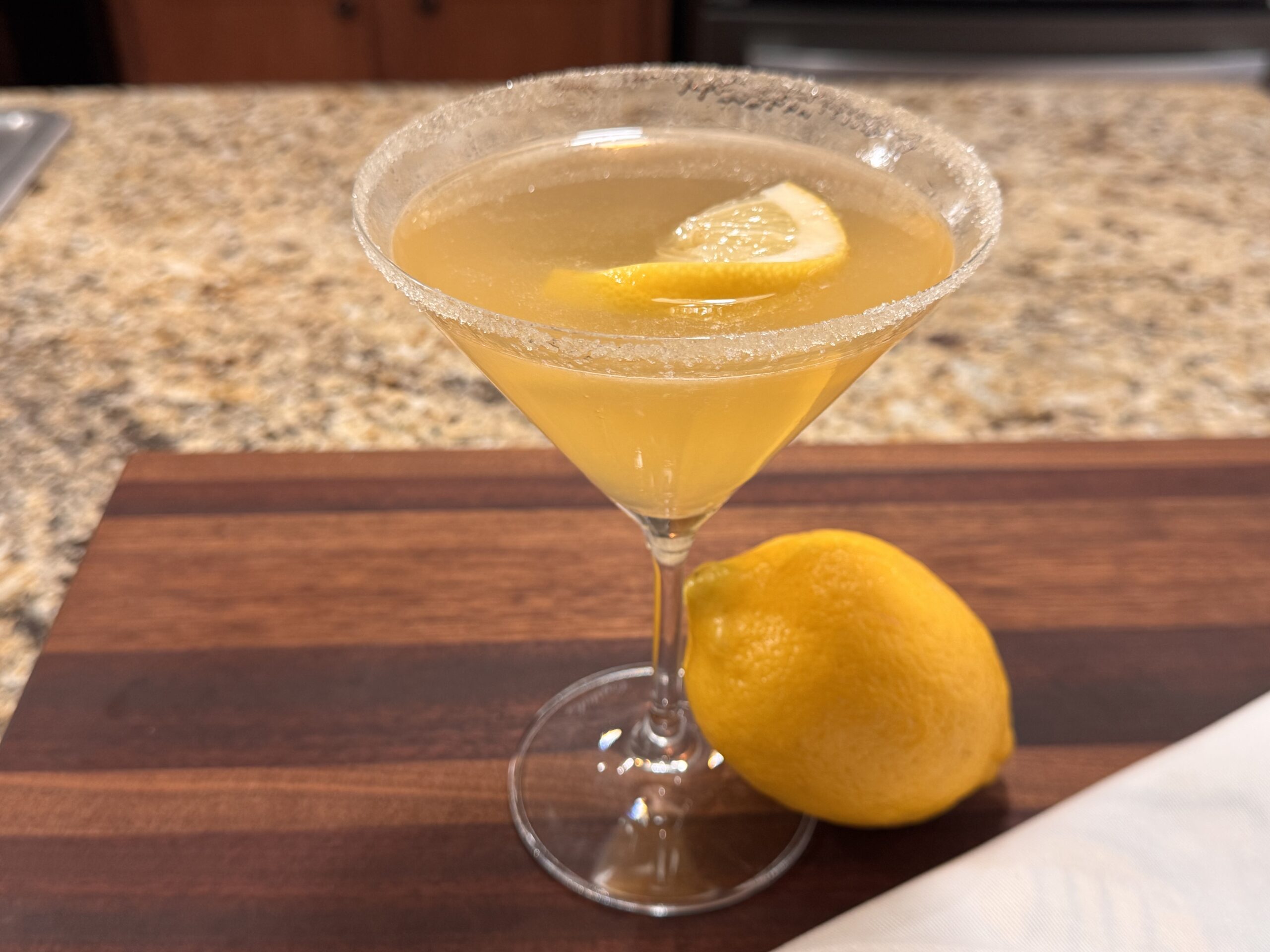 Lemon drop martini in martini glass with lemon on cutting board